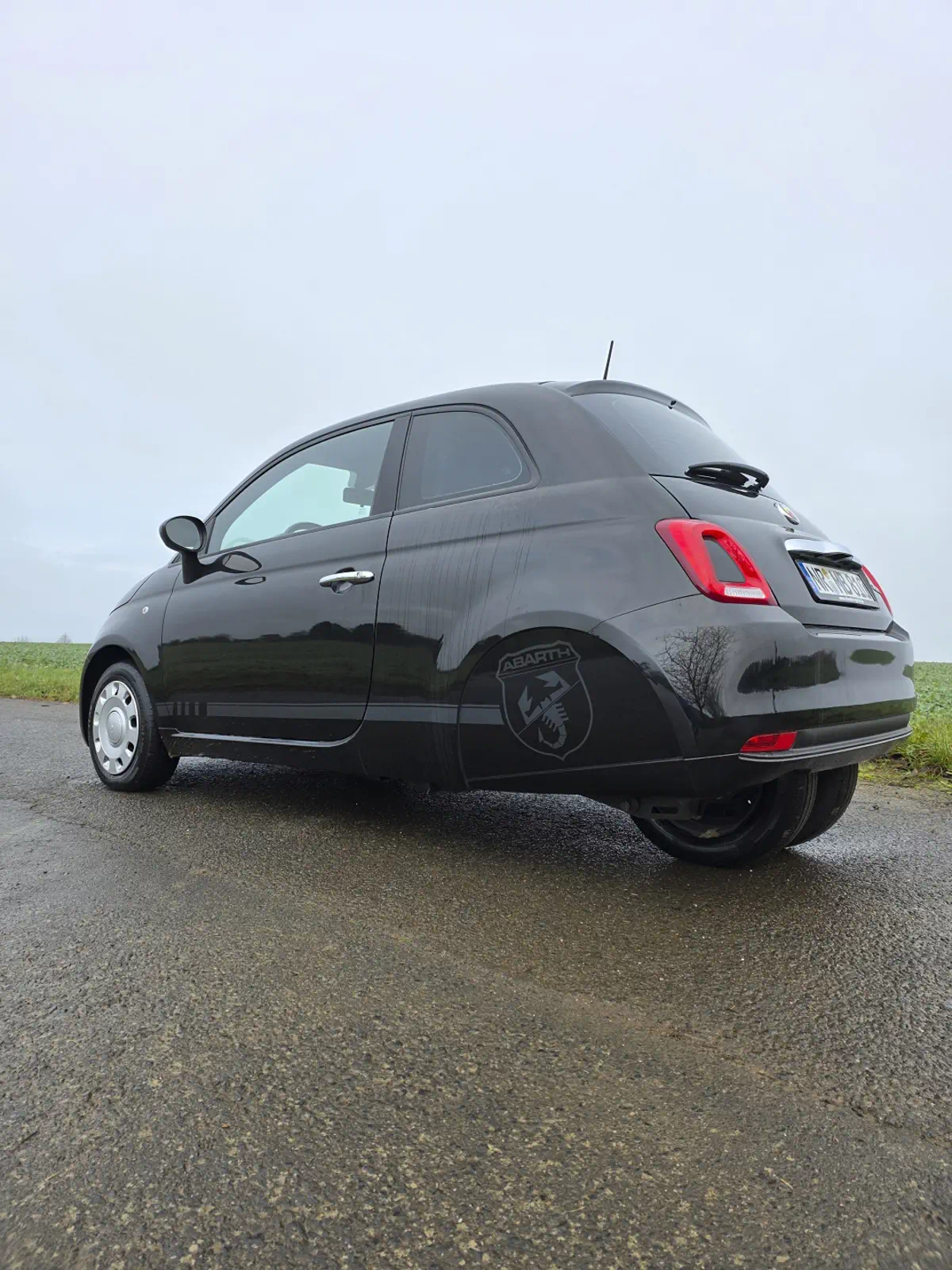 Schwarzer Abarth mit dezenter Folierung, professionelle Fahrzeugbeschriftung mit sportlichem Akzent.