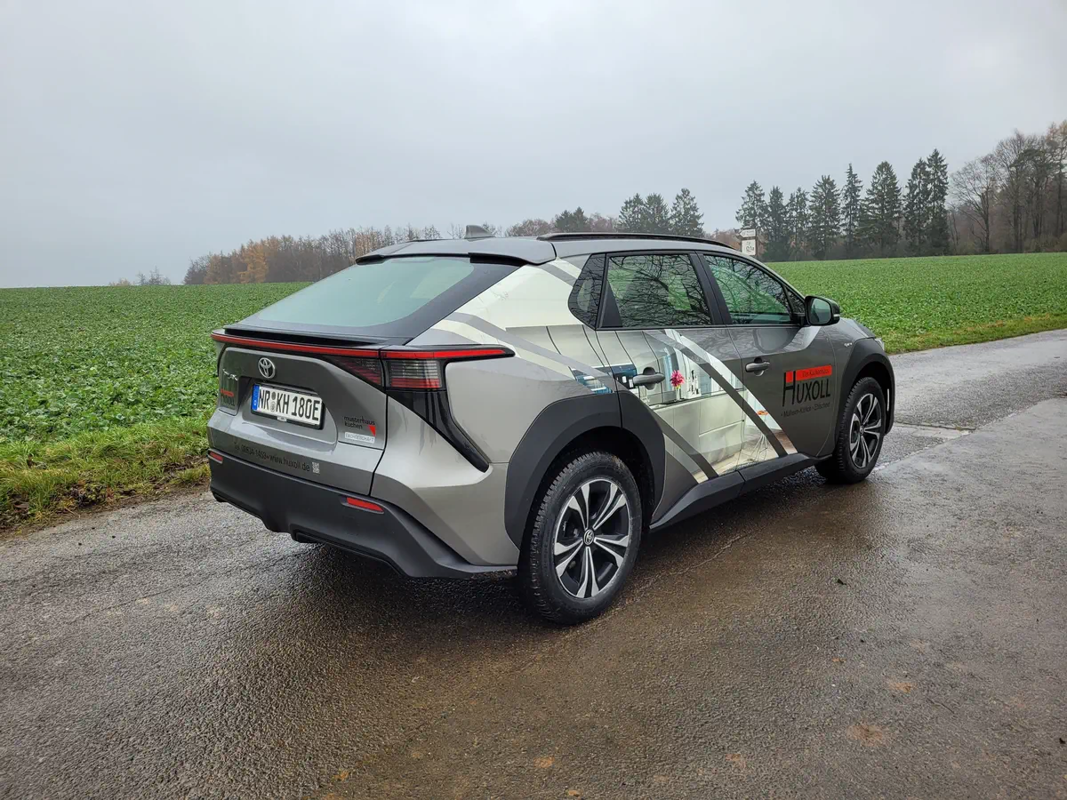 Grauer Toyota mit auffälliger Huxoll-Fahrzeugbeschriftung, professionell foliert für maximale Werbewirkung im Event-Branding.