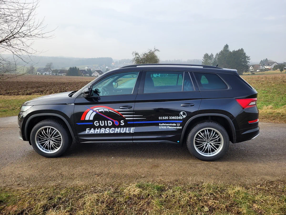 Kodiaq mit auffälliger Fahrzeugbeschriftung für 'Guido's Fahrschule', professionell foliert und ideal für Werbezwecke im Straßenverkehr.