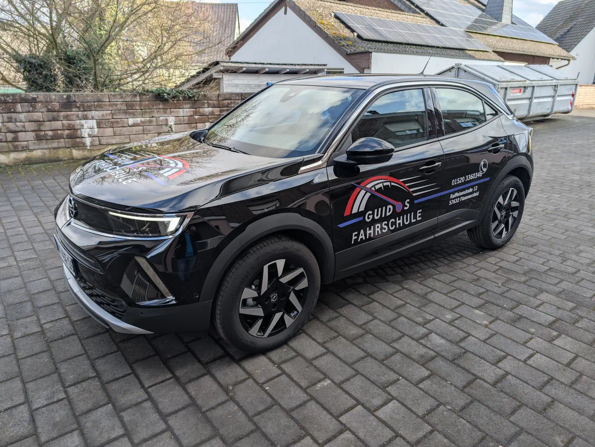 Schwarz folierter Opel Mokka mit auffälliger Fahrschulbeschriftung. Professionelles Car Wrapping für optimale Werbewirkung.